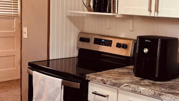 A kitchen with a stainless steel stove, white cabinets, and a countertop with a coffee maker.