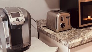 A kitchenette with a coffee maker, toaster, and microwave.