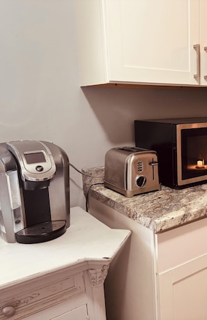 A kitchenette with a coffee maker, toaster, and microwave.
