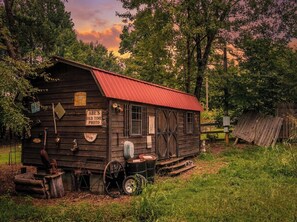 Ein rustikales Holzgebäude mit rotem Dach, beschriftet mit 'ABE'S OLD TIME PHOTO', umgeben von Grün und Bäumen.