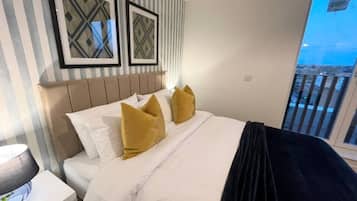A hotel room with a bed, a nightstand, a lamp, and a window with a view.