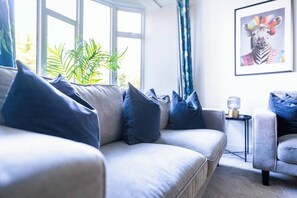 Ein Wohnzimmer mit einer Couch, Kissen, einem Beistelltisch und einem gerahmten Bild an der Wand.