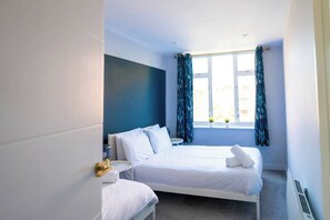 A hotel room with a bed, bedside tables, a window with curtains, and a view of the outside. - #137 StylishApart BournemouthBeach&Pier| for 10 (Bournemouth)
