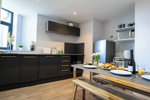Eine moderne Küche mit dunklen Schränken, einem Holztisch und Frühstücksgebäck.