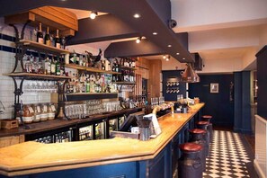 A bar area with shelves of bottles, glasses, and a bar counter with stools. - #137 StylishApart BournemouthBeach&Pier| for 10 (Bournemouth)
