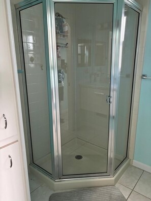 A corner shower with a glass door, a tiled floor, and a small step leading into the shower. - 2-bedroom modular home in wonderful Long Key with beautiful ocean views/sunsets (Layton)