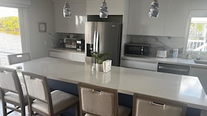 A modern kitchen with a large island, stainless steel appliances, and pendant lighting. - 2-bedroom modular home in wonderful Long Key with beautiful ocean views/sunsets (Layton)