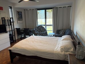 A hotel room with a bed, a desk, a chair, a television, and a window with curtains. - Ocean Views Studio Apartment with Secure Parking, walk to shops and the beach. (St Kilda)