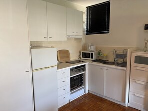 A compact kitchen with white cabinets, a microwave, a toaster, and a sink. - Ocean Views Studio Apartment with Secure Parking, walk to shops and the beach. (St Kilda)