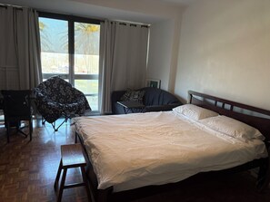 Ett hotellrum med en säng, en stol, ett litet bord och utsikt genom ett fönster.