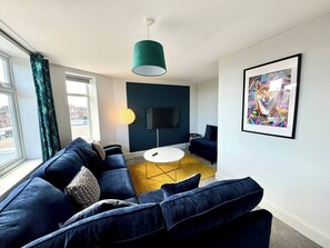 A modern living room with a sofa set, a coffee table, and a flat-screen TV. - #139 Large coastal apartment near Beach|sleeps 10 (Bournemouth)
