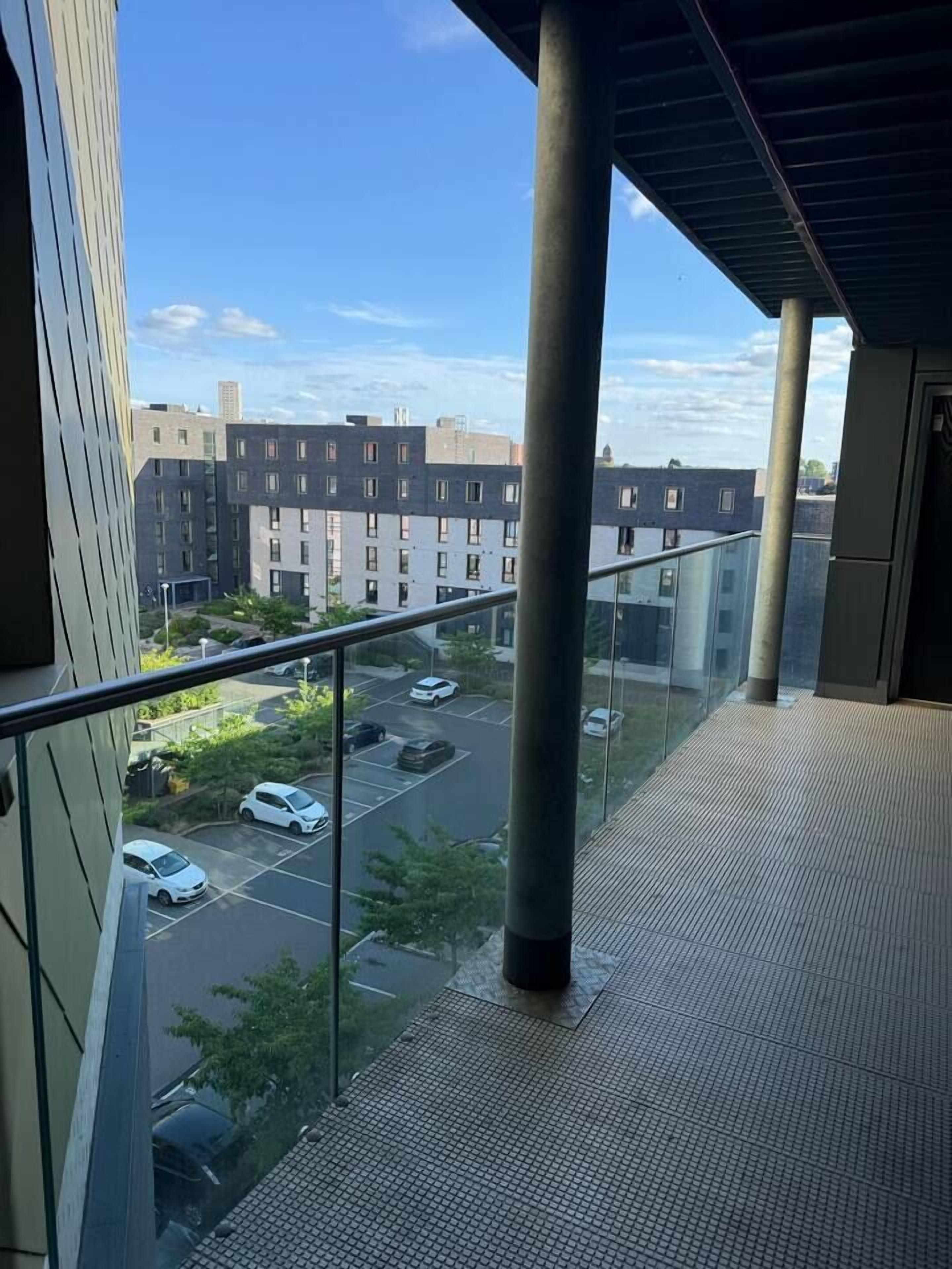 Ein Balkon mit Blick auf einen Parkplatz und Gebäude.
