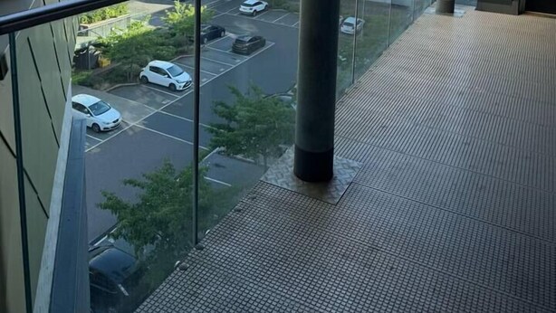 Uma varanda com vista para um estacionamento e edifícios.