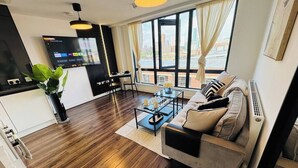Uma sala de estar moderna com sofá, mesa de centro e televisão fixada na parede.