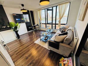 Ein modernes Wohnzimmer mit einer Couch, einem Couchtisch und einem an der Wand montierten Fernseher.