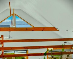 A room with a sloped ceiling, wooden beams, and a view of the outdoors.