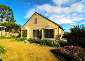 A single-story house with a sloped roof, a front porch, and a fenced yard.