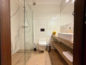 Une salle de bain moderne avec une douche à parois de verre, des toilettes blanches et un meuble-lavabo en bois avec un évier.