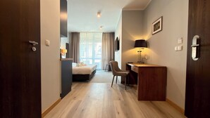 Une chambre d’hôtel avec un lit, un bureau, une chaise et une vue par la fenêtre.