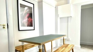 A room with a wooden table and bench, a framed picture on the wall, and a white door. - #141 Coastal Apartment BournemouthBeach| Sleeps 10 (Bournemouth)