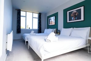 Une chambre d’hôtel avec deux lits, une grande fenêtre et un tableau au mur.