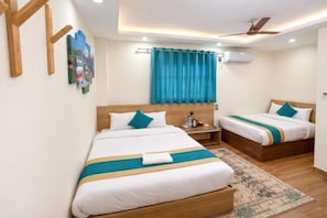 Habitación de hotel con dos camas, ventilador de techo, aire acondicionado y una alfombra estampada.