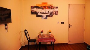 Quarto com uma mesa de jantar, uma cadeira, um quadro na parede e uma porta fechada.