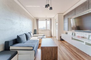 A modern living room with a sofa, a coffee table, and a TV mounted on the wall. - Paryska Deluxe Apartment (Kołobrzeg)