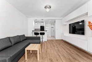 Una sala de estar moderna con un sofá modular, una mesa de centro de madera y un televisor montado en la pared.