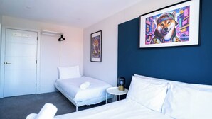 A hotel room with a bed, a bedside table, a chair, a door, and two framed artworks on the wall. - #142 Bournemouth Flat| Near AlumChine Beach|for 10 (Bournemouth)