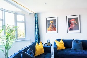A room with a blue sofa, yellow pillows, a plant, and two framed pictures on the wall. - #142 Bournemouth Flat| Near AlumChine Beach|for 10 (Bournemouth)