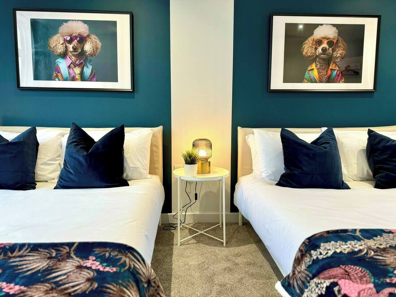 A hotel room with two beds, each with a pillow and a framed picture on the wall.