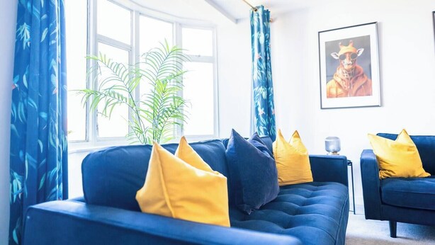 A modern living room with a blue sofa set, yellow cushions, a potted plant, and a framed picture on the wall. - #142 Bournemouth Flat| Near AlumChine Beach|for 10 (Bournemouth)