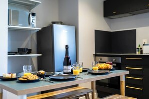 Eine moderne Küche mit Esstisch, gedeckt für das Frühstück, inklusive Weinflasche, Gläsern und Gebäck.