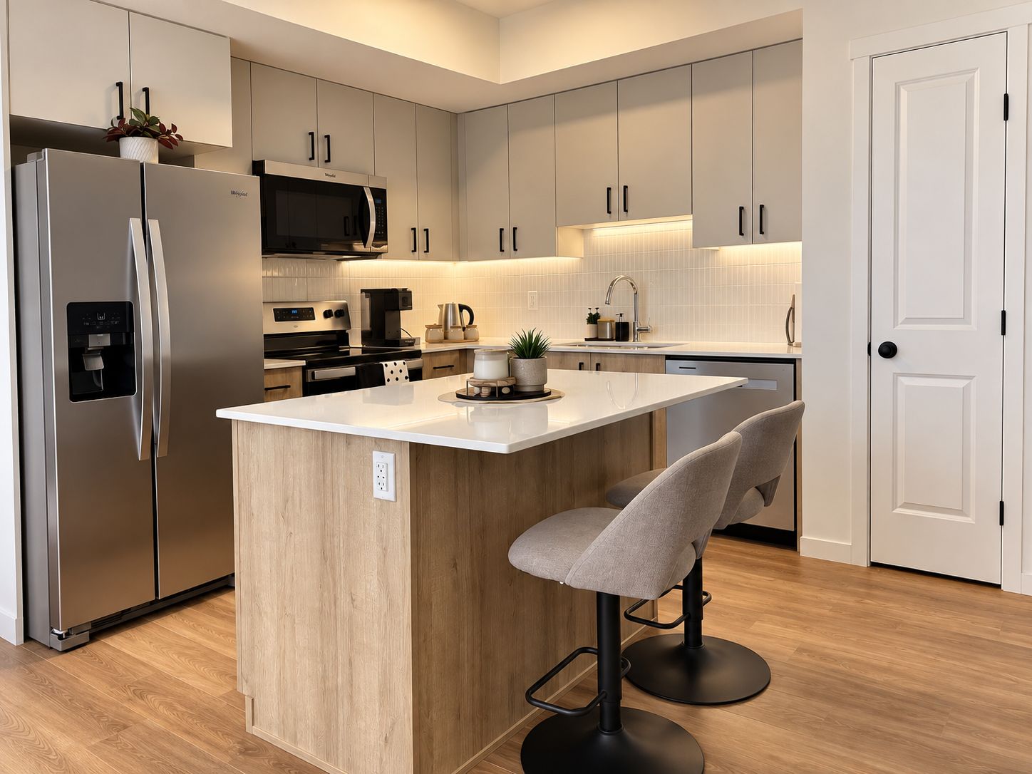 A modern kitchen with a central island, stainless steel appliances, and light wood cabinetry.