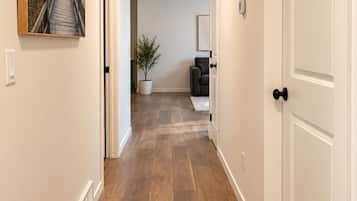 A hallway with wooden flooring, white walls, and a door on the right.