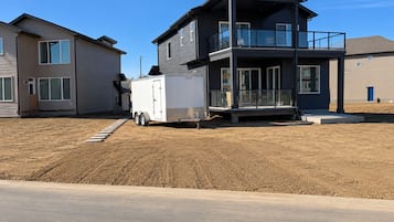 A two-story residential building with a balcony and a white trailer parked in front.
