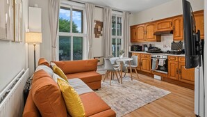 Una cocina moderna con armarios de madera, un comedor con mesa y sillas, y una sala de estar con sofá y alfombra.