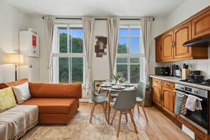 Ein gemütlicher Wohnraum mit Sofa, Esstisch, Stühlen und einer Küchenzeile.