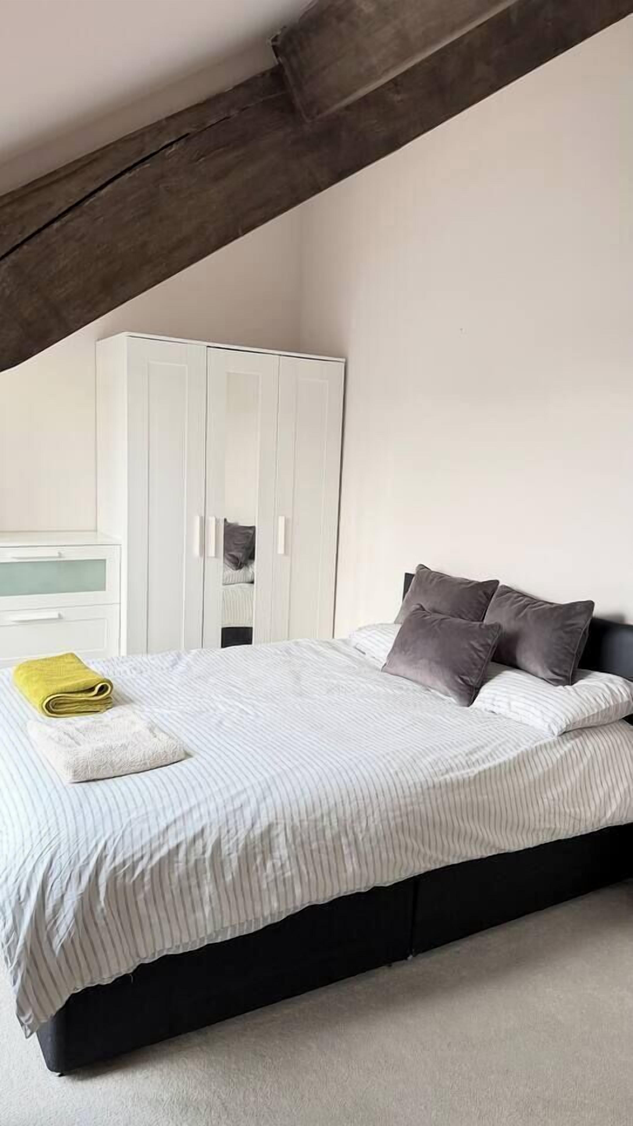 Ein Schlafzimmer mit Bett, Schrank und sichtbarem Deckenbalken.