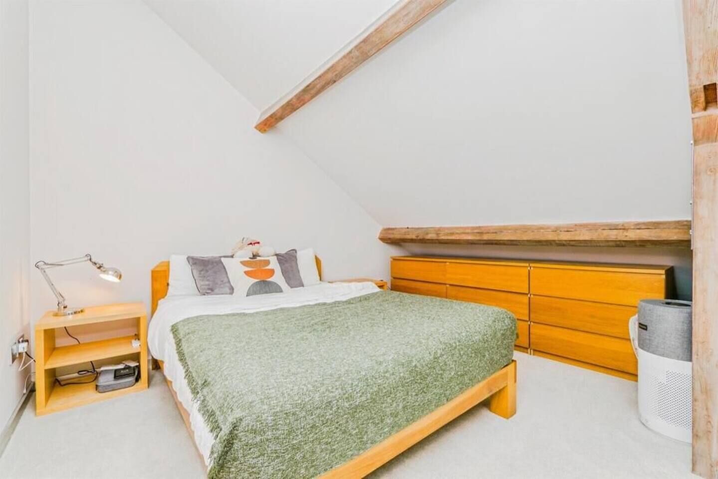 Une chambre à coucher avec un lit, une commode en bois, une table de chevet et une lampe.