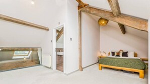 A bedroom with a sloped ceiling, a bed with a green cover, a wooden headboard, and a skylight. - Unique apartment in Cardiff (Pontcanna)