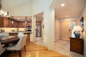 A modern kitchen with wooden cabinets, stainless steel appliances, and a dining area with a table and chairs. - Cascades at EagleRidge Stuart 4 | Hot Tub | AC | Walk to Resort (Steamboat Springs)