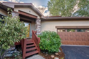 A residential house with a stone column, a wooden staircase, a garage door, and a well-maintained garden. - Cascades at EagleRidge Stuart 4 | Hot Tub | AC | Walk to Resort (Steamboat Springs)