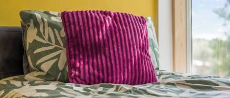 A bed with a patterned bedspread and a pillow with a leaf design.