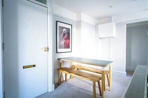 A room with a white door, a framed picture on the wall, a wooden bench, and a table. - #159 Sunny Stay Near the Bournemouth Beach -For 9 (Bournemouth)