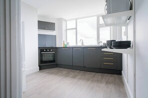 A modern kitchen with grey cabinets, a black oven, and a window above the sink. - #159 Sunny Stay Near the Bournemouth Beach -For 9 (Bournemouth)