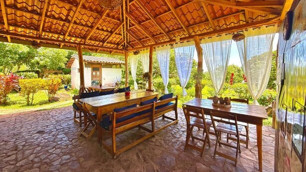 An outdoor covered patio with wooden furniture and a stone floor. - finca montania sagrada Ometepe (Mérida)