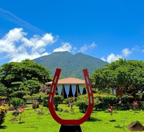Una escultura en forma de herradura en un jardín, con una montaña al fondo.