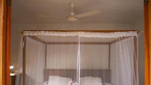 A bed with a canopy, a ceiling fan, and a stone floor. - finca montania sagrada Ometepe (Mérida)